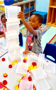 Boy buiding tower with plastic boxes